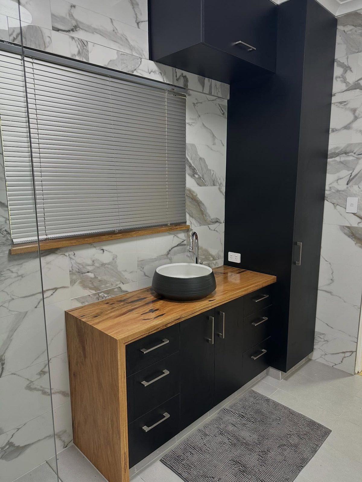 After: black vanity drawers with a Curly Marri timber top and round basin