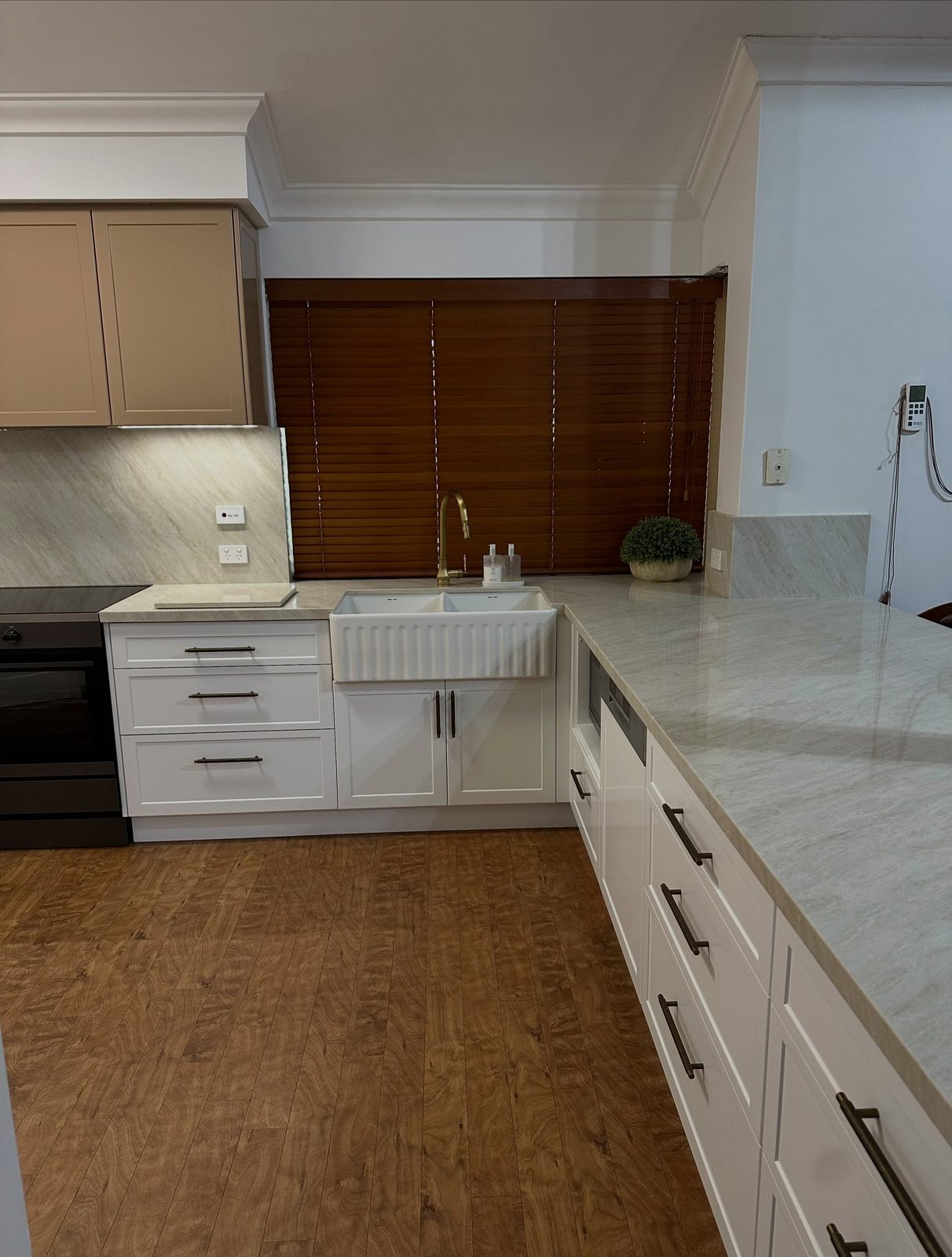 After: white stone-look benchtop with a butler's sink and timber blinds