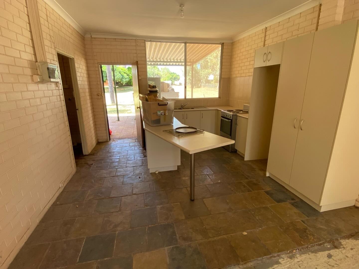 Before: a tired kitchen with exposed brick walls, a timber door and a tiled floor