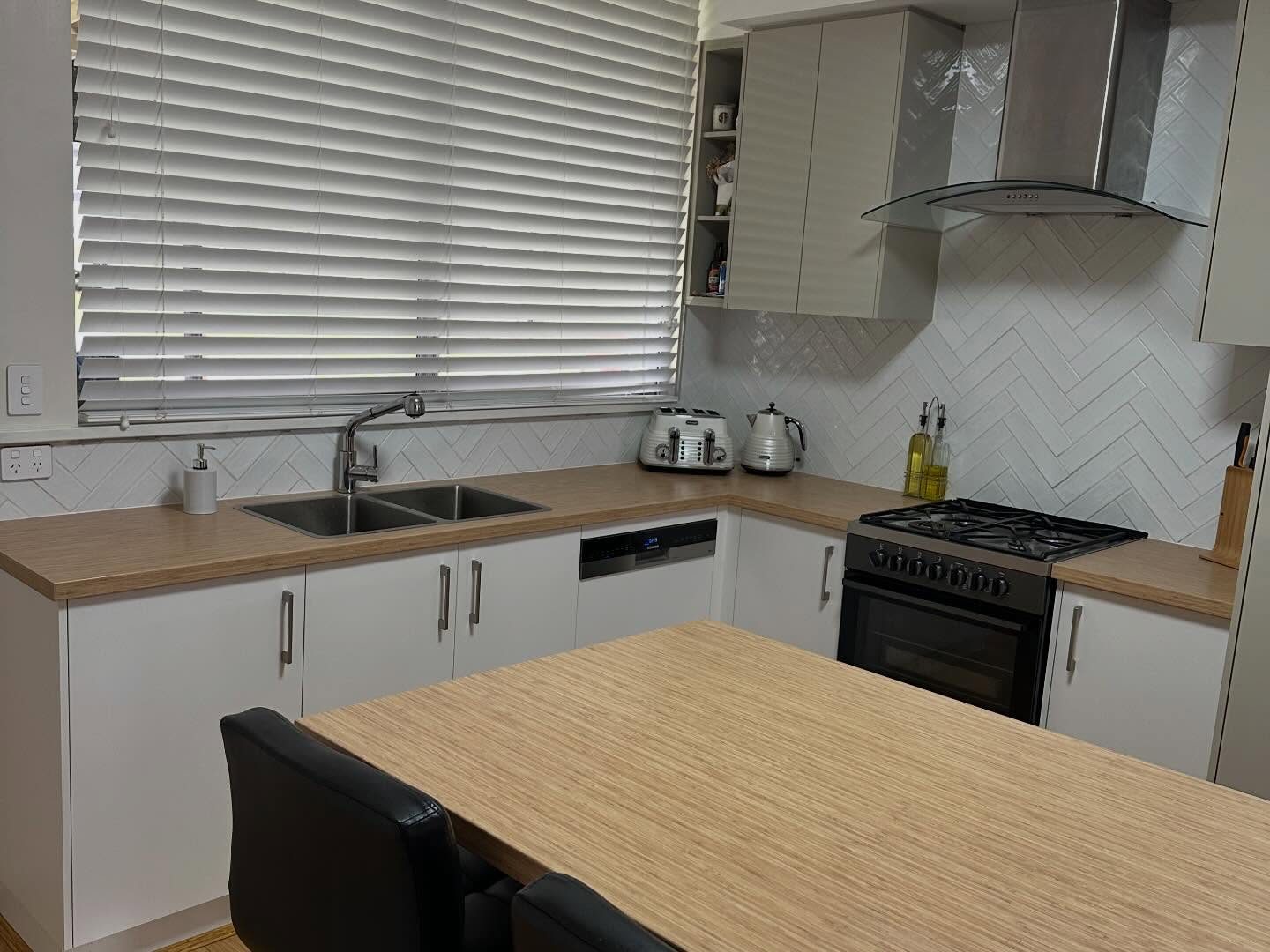 After: white kitchen with a gas cooktop, rangehood and herringbone splashback
